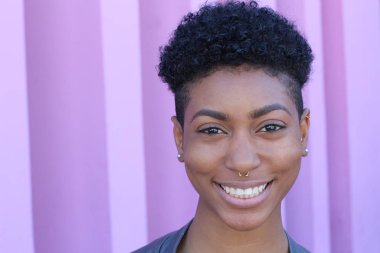 Mor duvar arkasında kısa kıvırcık saçlı güzel bir Afrikalı kadının yakın plan portresi. 