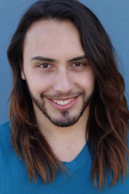 Mavi duvarın önünde uzun saçlı yakışıklı genç adamın yakın plan portresi.