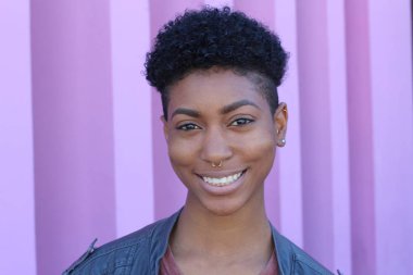 Mor duvar arkasında kısa kıvırcık saçlı güzel bir Afrikalı kadının yakın plan portresi. 