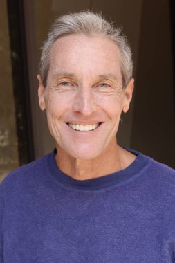 Kameraya bakan mor kazaklı yakışıklı olgun bir adamın yakın plan portresi.