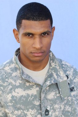 Mavi duvarın önünde üniformalı yakışıklı Afro-Amerikan askerinin yakın plan portresi