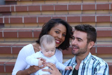 Yeni doğmuş bebeklerine sarılan ırklar arası bir çift.