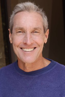 Kameraya bakan mor kazaklı yakışıklı olgun bir adamın yakın plan portresi.