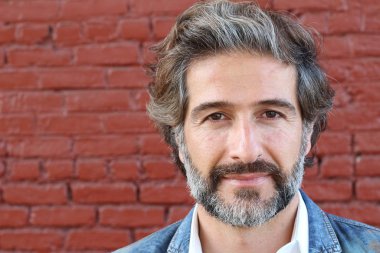 Tuğla duvarın önünde takım elbiseli yakışıklı bir iş adamının yakın plan portresi.