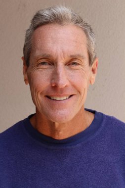 Kameraya bakan mor kazaklı yakışıklı olgun bir adamın yakın plan portresi.