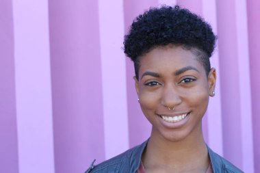 Mor duvar arkasında kısa kıvırcık saçlı güzel bir Afrikalı kadının yakın plan portresi. 