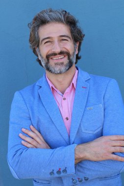 Mavi duvarın önünde pembe gömlekli yakışıklı yetişkin bir adamın yakın plan portresi.