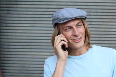 Sokakta telefonla konuşan, uzun saçlı, yakışıklı bir genç adamın yakın plan portresi.