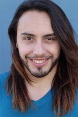 Mavi duvarın önünde uzun saçlı yakışıklı genç adamın yakın plan portresi.