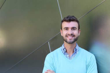 İşaretli gömlekli genç bir adam portresi ve kolları çapraz duran cyan süveter.