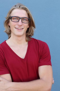 Mavi duvarın önünde uzun saçlı yakışıklı ve şık bir adamın yakın plan portresi.