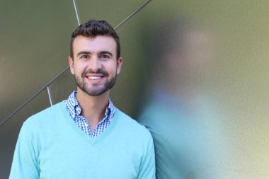 İşaretli gömlekli genç bir adam portresi ve kolları çapraz duran cyan süveter.