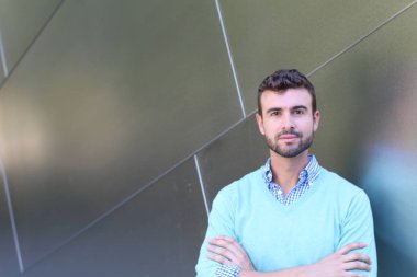 İşaretli gömlekli genç bir adam portresi ve kolları çapraz duran cyan süveter.