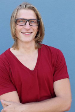 Mavi duvarın önünde uzun saçlı yakışıklı ve şık bir adamın yakın plan portresi.