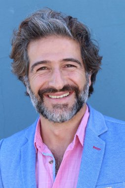 Mavi takım elbiseli ve mavi gömlekli yakışıklı bir iş adamının mavi duvarın önünde yakın plan portresi.