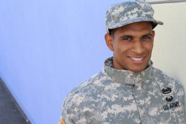 Mavi duvarın önünde üniformalı yakışıklı Afro-Amerikan askerinin yakın plan portresi