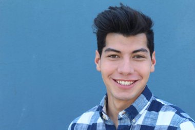 Mavi duvarın önünde poz veren yakışıklı genç adamın yakın plan portresi.