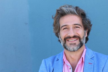 Mavi takım elbiseli ve mavi gömlekli yakışıklı bir iş adamının mavi duvarın önünde yakın plan portresi.