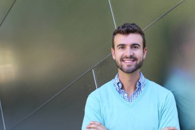 İşaretli gömlekli genç bir adam portresi ve kolları çapraz duran cyan süveter.