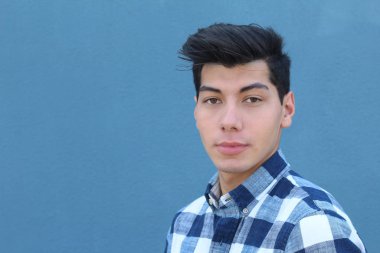 Mavi duvarın önünde poz veren yakışıklı genç adamın yakın plan portresi.