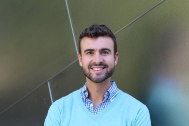 İşaretli gömlekli genç bir adam portresi ve kolları çapraz duran cyan süveter.