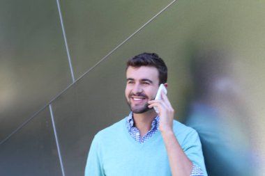 Kareli gömlekli genç bir adamın portresi ve telefonda konuşan Cyan süveteri. 