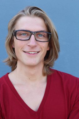 Mavi duvarın önünde uzun saçlı yakışıklı ve şık bir adamın yakın plan portresi.