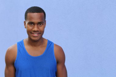 Mavi duvarın önündeki yakışıklı Afrikalı Amerikalı genç adamın yakın plan portresi.
