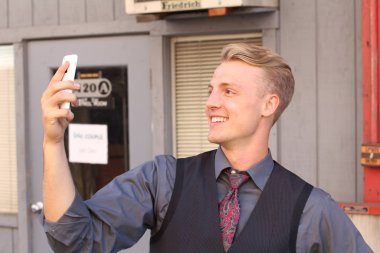 İngiliz centilmen güzellik konsepti. Dışarıda telefon kullanan genç ve yakışıklı bir adamın portresi. 