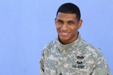 Mavi duvarın önünde üniformalı yakışıklı Afro-Amerikan askerinin yakın plan portresi