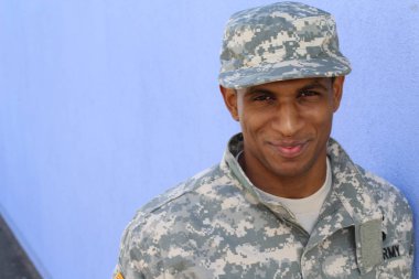 Mavi duvarın önünde üniformalı yakışıklı Afro-Amerikan askerinin yakın plan portresi