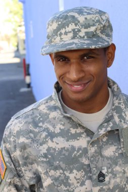 Mavi duvarın önünde üniformalı yakışıklı Afro-Amerikan askerinin yakın plan portresi
