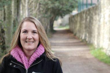 Güler yüzlü sarışın kadın güz parkında gündüz vakti duruyor.