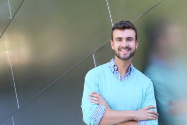 İşaretli gömlekli genç bir adam portresi ve kolları çapraz duran cyan süveter.