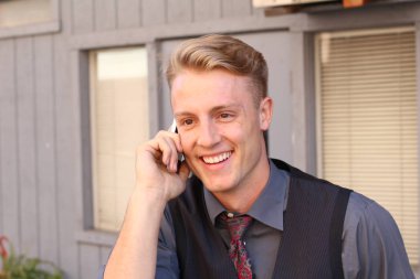 İngiliz centilmen güzellik konsepti. Dışarıda telefon kullanan genç ve yakışıklı bir adamın portresi. 