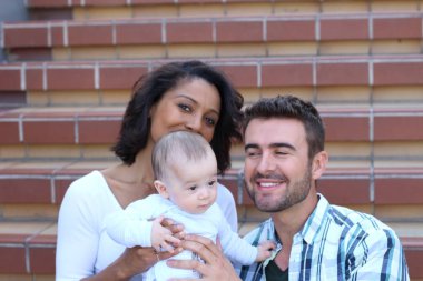 Yeni doğmuş bebeklerine sarılan ırklar arası bir çift.