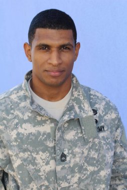 Mavi duvarın önünde üniformalı yakışıklı Afro-Amerikan askerinin yakın plan portresi