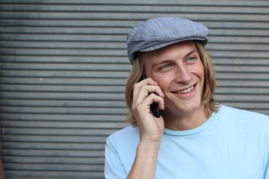 Sokakta telefonla konuşan, uzun saçlı, yakışıklı bir genç adamın yakın plan portresi.