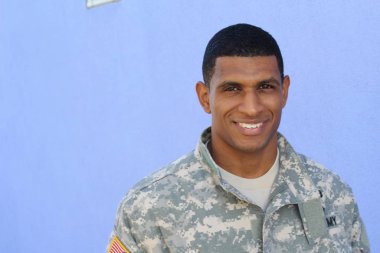 Mavi duvarın önünde üniformalı yakışıklı Afro-Amerikan askerinin yakın plan portresi