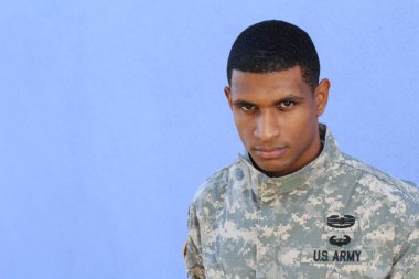 Mavi duvarın önünde üniformalı yakışıklı Afro-Amerikan askerinin yakın plan portresi