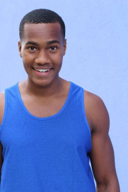 Mavi duvarın önündeki yakışıklı Afrikalı Amerikalı genç adamın yakın plan portresi.