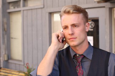 İngiliz centilmen güzellik konsepti. Dışarıda telefon kullanan genç ve yakışıklı bir adamın portresi. 