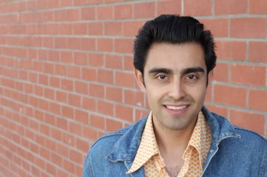 Kırmızı tuğla duvarın arka planında iyi bir adamın yakın plan portresi.