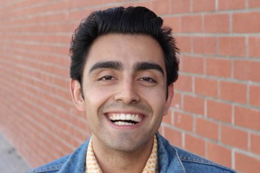 Kırmızı tuğla duvarın arka planında iyi bir adamın yakın plan portresi.