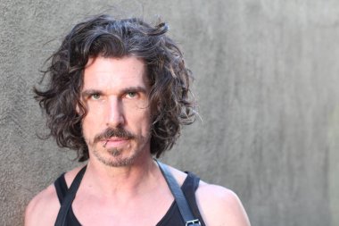 Bıyıklı ve uzun kıvırcık saçlı yakışıklı genç adamın yakın plan portresi.