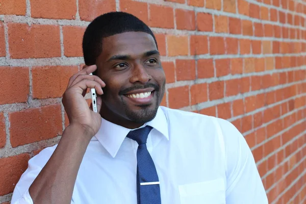 Portrait of good looking businessman or manager talking on phone, brick wall background
