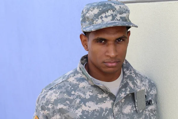 Mavi duvarın önünde üniformalı yakışıklı Afro-Amerikan askerinin yakın plan portresi