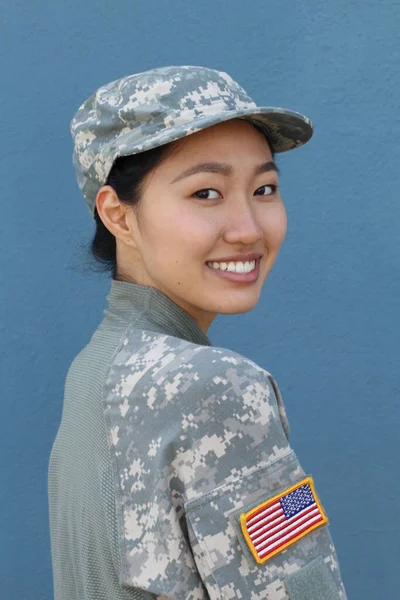 Portrait of serious female army soldier against blue background