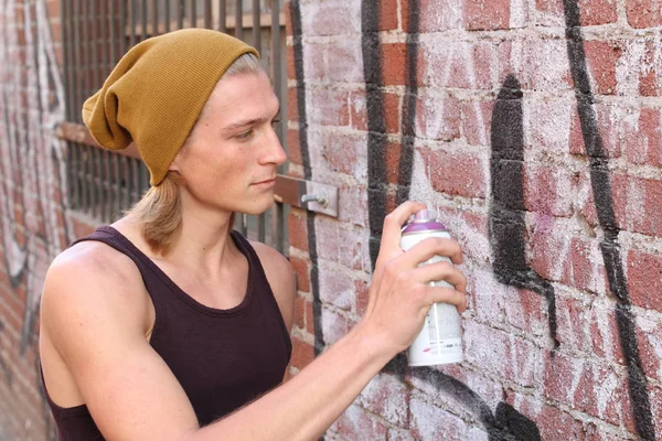close-up portrait of handsome young graffiti artist with long hair on city street
