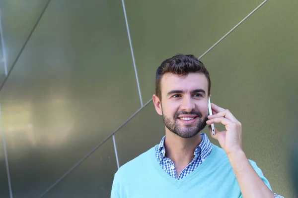 Portrait of young man in checked shirt and cyan sweater talking on phone